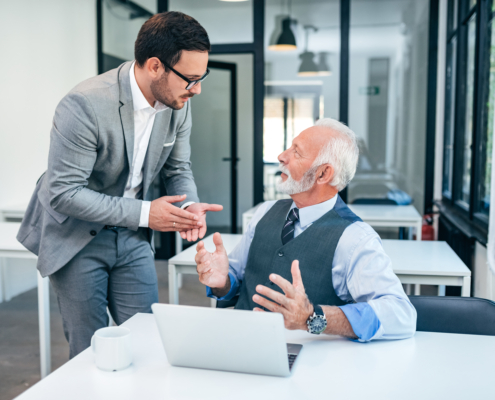 Senior And Young Man Discussing At Work.