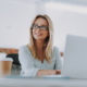 Positive Businesswoman Sitting With Laptop And Looking Away